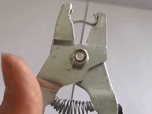 A worker is holding a pair of pliers.